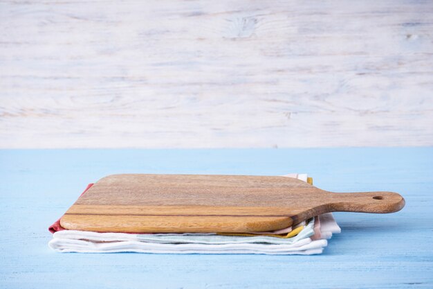 Wooden cutting board on wooden table, place for text.