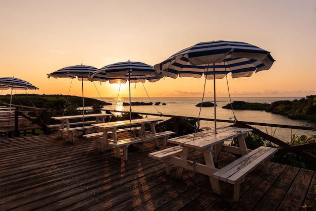 Wooden deck with parasol and benches being illuminated by sunset