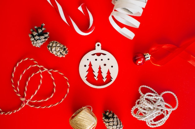 Wooden decoration on the Christmas tree on a red background surrounded by Christmas elements.