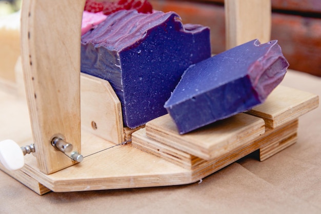 Wooden device for cutting soap handmade with a freshly cut purple bar of soap Close up