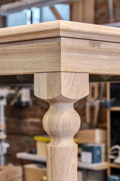 Wooden dining table with carved leg of solid oak and metal frame build process in workshop closeup