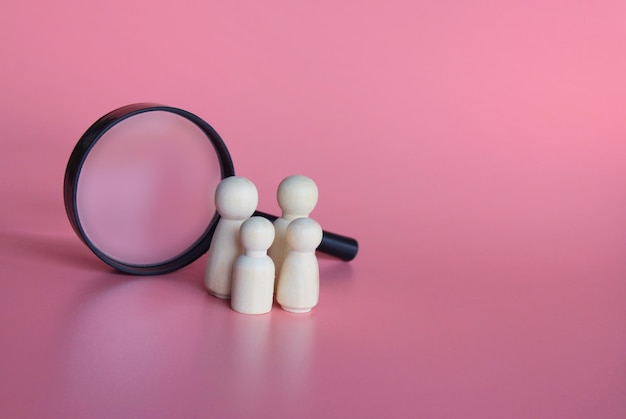 Wooden dolls and magnifying glass Finding a partner to create a family adoption of kid concept