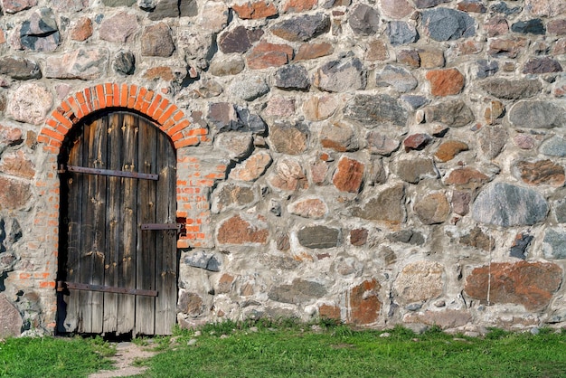 Wooden door in a wall of uneven stones Vintage building background