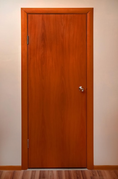 Wooden door with metal pen on a blank wall