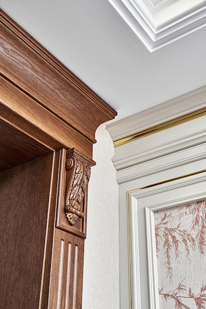 Wooden doorway with carved furniture brackets and fluted panel and wall panel with golden molding