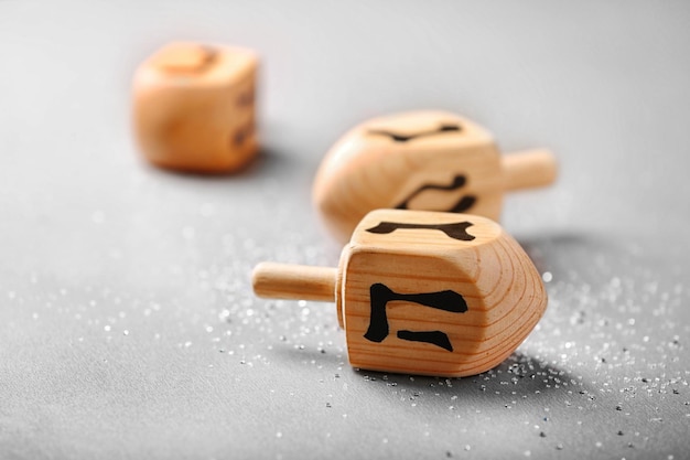 Wooden dreidel for Hanukkah on light background