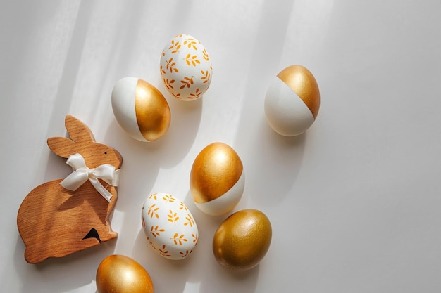 Wooden Easter Bunny and golden eggs on white background Holiday concept Happy Easter