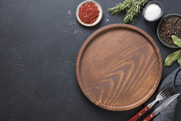 wooden empty plate, spices and ingredients for cooking. View from above.