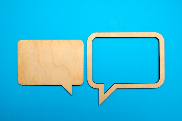 Wooden empty speech bubbles concept on blue paper background with drop shadow Copy space