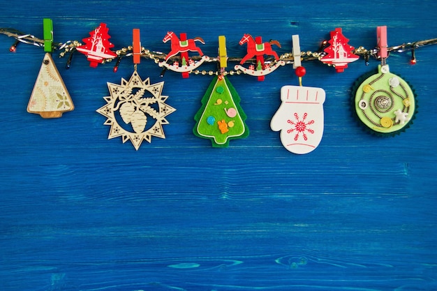 Wooden and felt Christmas decorations and Christmas lights on a rope on the blue wooden background top view