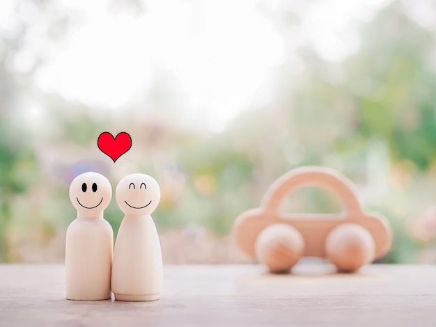 Wooden figure of happy couple with wooden toy car The concept of happy family