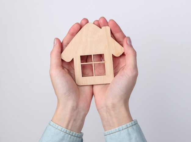 Wooden figurine house in female hands on a white