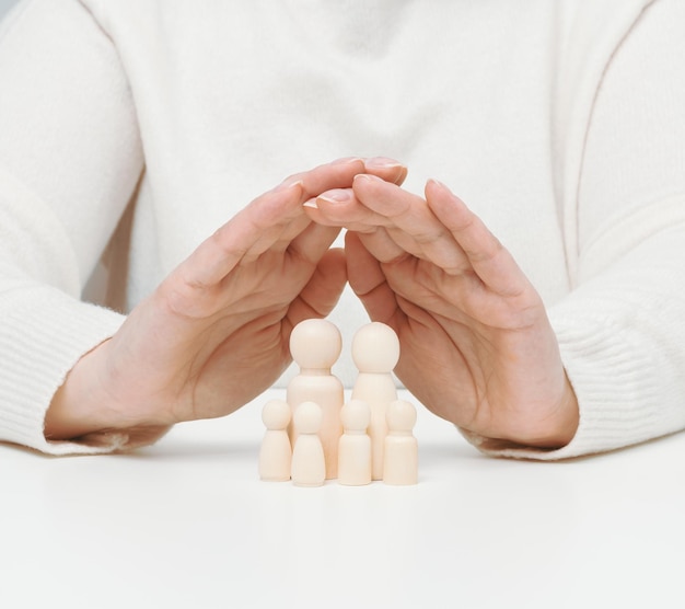 Wooden figurines of men a family guarded by two female hands