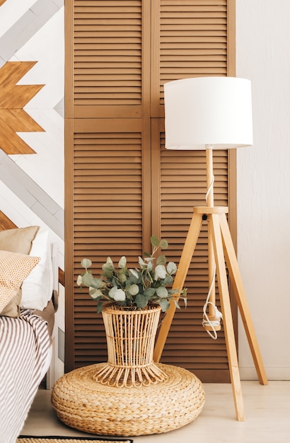 Wooden floor lamp and plants near the bed