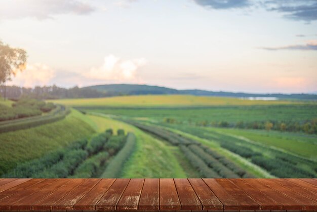 Wooden floor with beautiful sunset blur image of tea plantation background