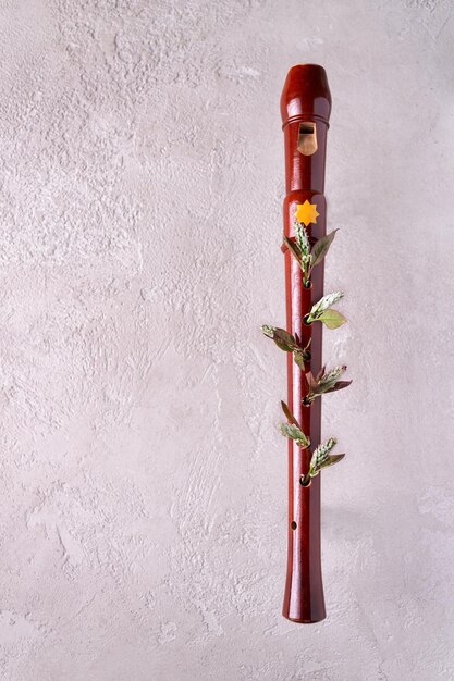 Wooden flute with young shoots on a light textured background copy space