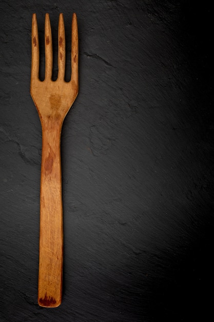 Wooden fork on black slate 