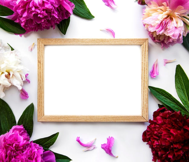 Wooden frame surrounded by beautiful pink peonies on a white background