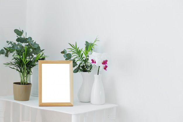 Wooden frame on vintage white shelf with flowers and plants