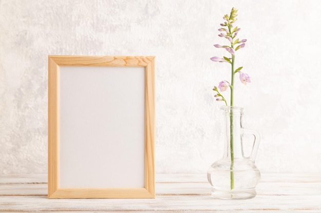 Wooden frame with hosta flowers in glass vase on gray concrete background side view copy space