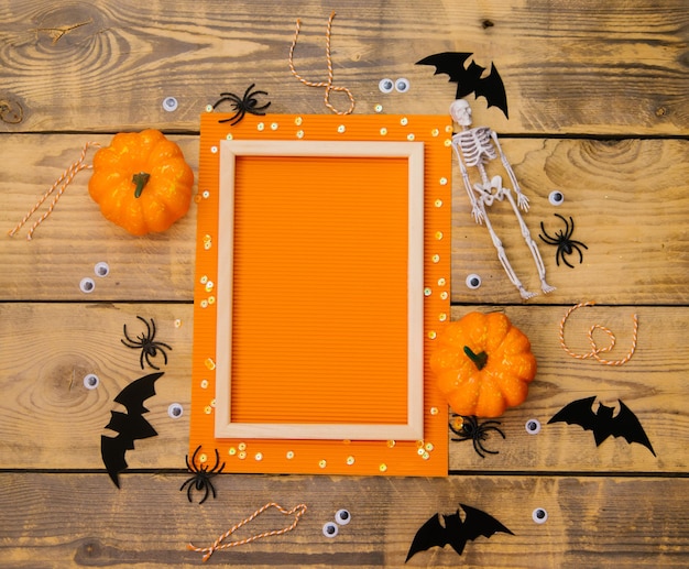 Wooden frame with pumpkin skeleton spiders and bats on a wooden background A festive Halloween theme Empty space for text