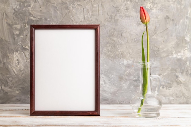 Wooden frame with red tulip flower in glass on gray concrete background side view copy space mockup