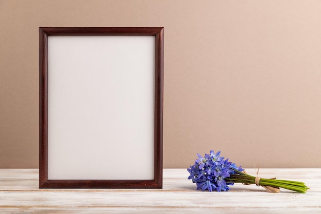 Wooden frame with spring snowdrop flowers bluebell on beige pastel background top view copy space mockup template