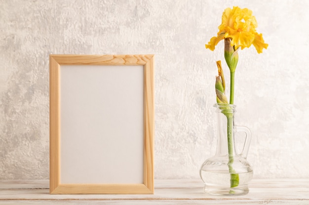 Wooden frame with yellow iris flower in glass on gray concrete background. side view, copy space