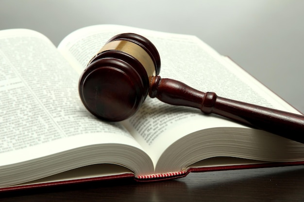 Wooden gavel and book on wooden table on grey background