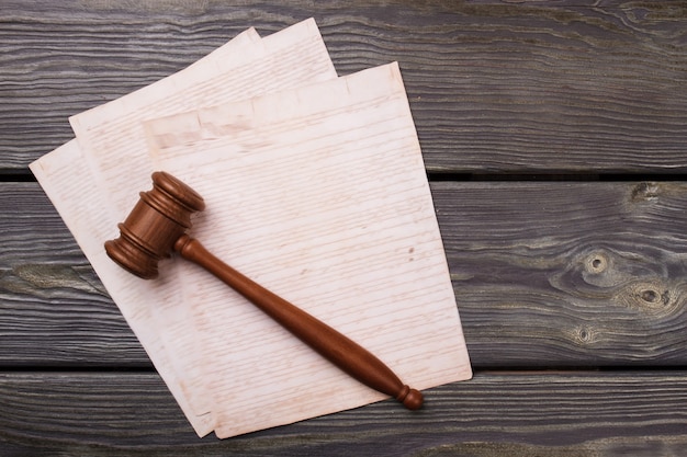 Photo wooden gavel and papers with. handwriting text on grey desk.