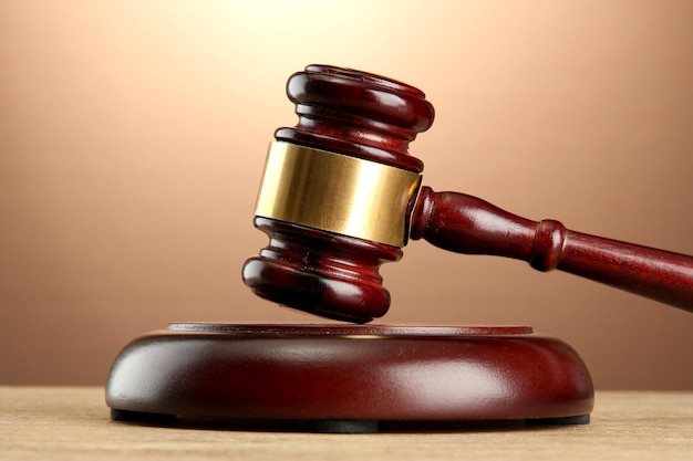 Wooden gavel on wooden table on brown background