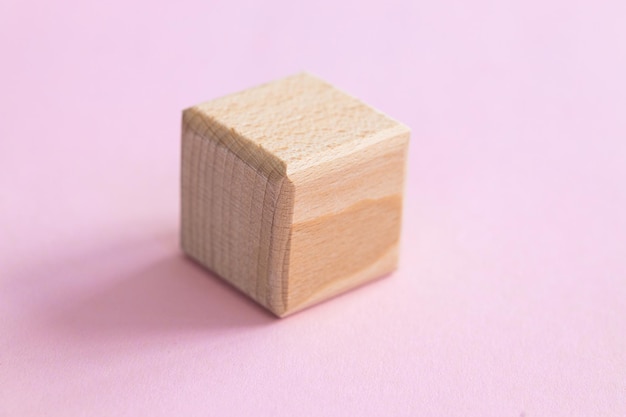 Wooden geometric shapes cube isolated on a pink