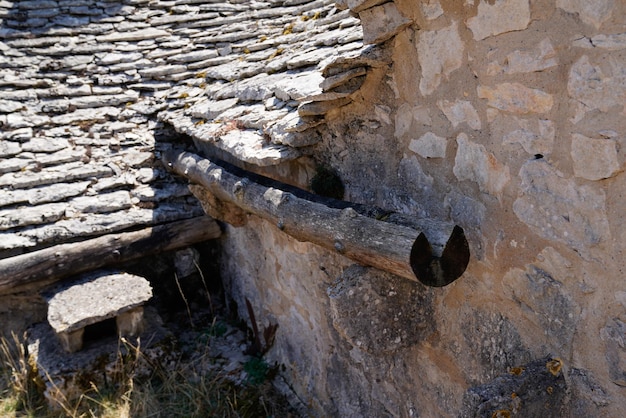 Wooden gutter from a medieval tree trunk or branch from a very old farmhouse wall roof tiles house