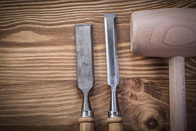 Wooden hammer firmer chisels on vintage wood board construction concept.