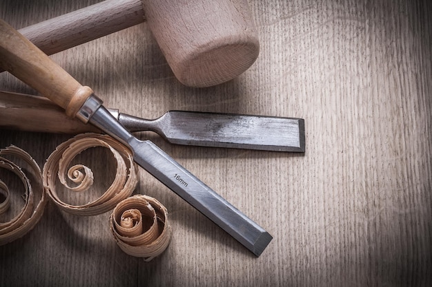 Wooden hammer planning chips flat chisels on wood board top view construction concept