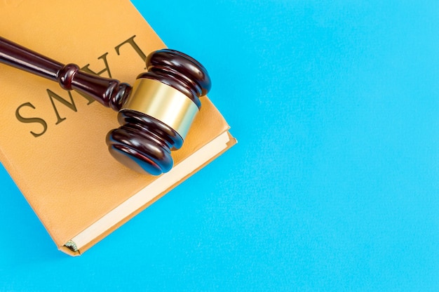 Photo wooden hammer with book which labeled laws on a blue background