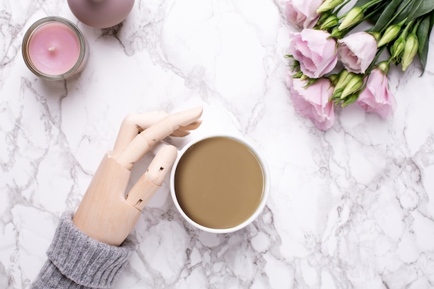 Wooden hand , coffee and pink flowers on marble