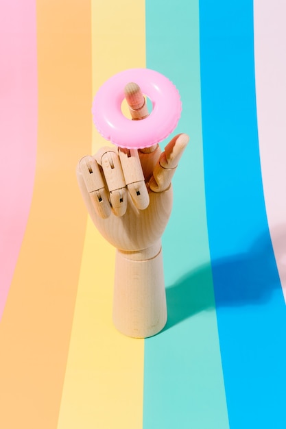 wooden hand with a float on the finger on a multicoloured background travel and summer 3d