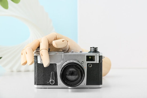 Wooden hand with photo camera on table, closeup