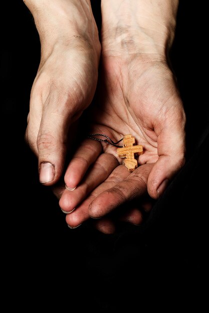 Wooden handmade cross in the palm of a peasant woman. Closeup