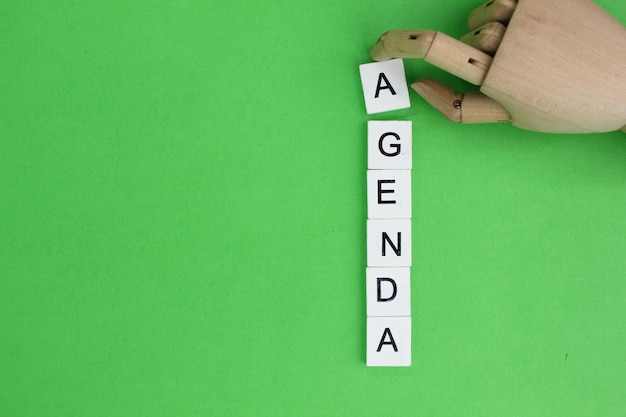 Wooden hands and alphabets with the word agenda The concept of todays agenda