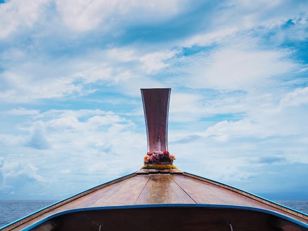 Wooden head longtail boat against blue sea and sky.