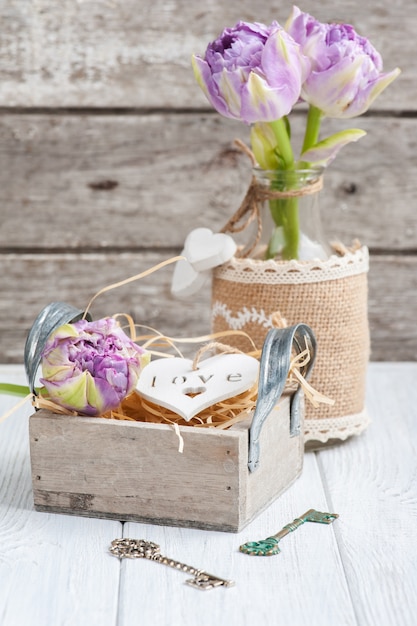 Wooden heart in vintage gift box with key and purple tulips