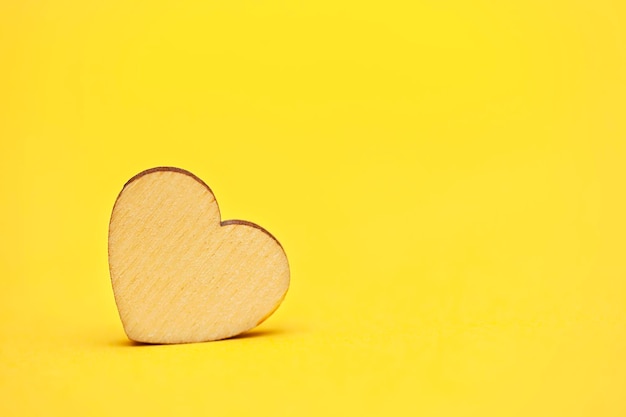 Wooden heart on yellow background copy space