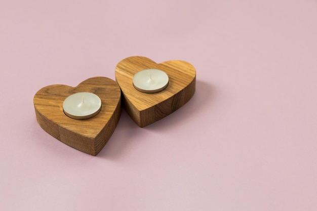 Wooden hearts on pink background Candles