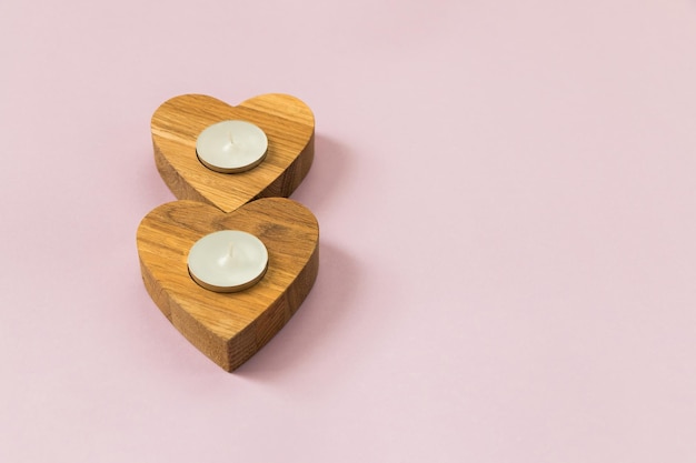 Wooden hearts on pink background Candles