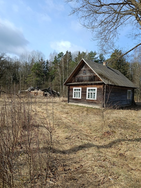 A wooden house in a field with a blue sky in the background.