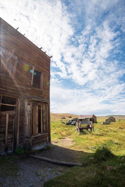 Wooden house in ghost town on field against sky