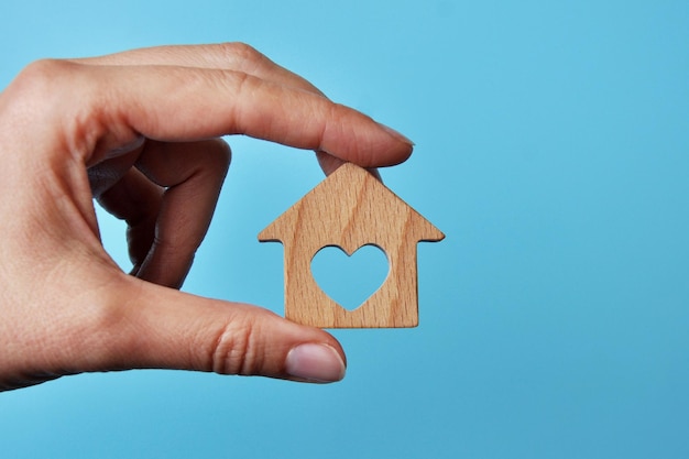 A wooden house in the hands of a man. A symbol of protection and care for home and family