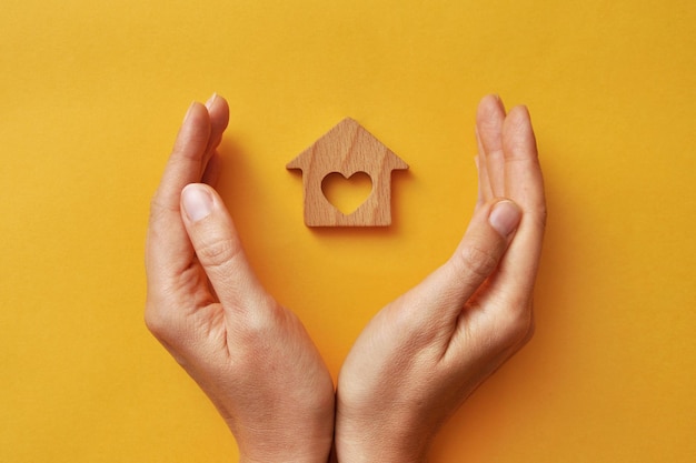 A wooden house in the hands of a man. A symbol of protection and care for home and family